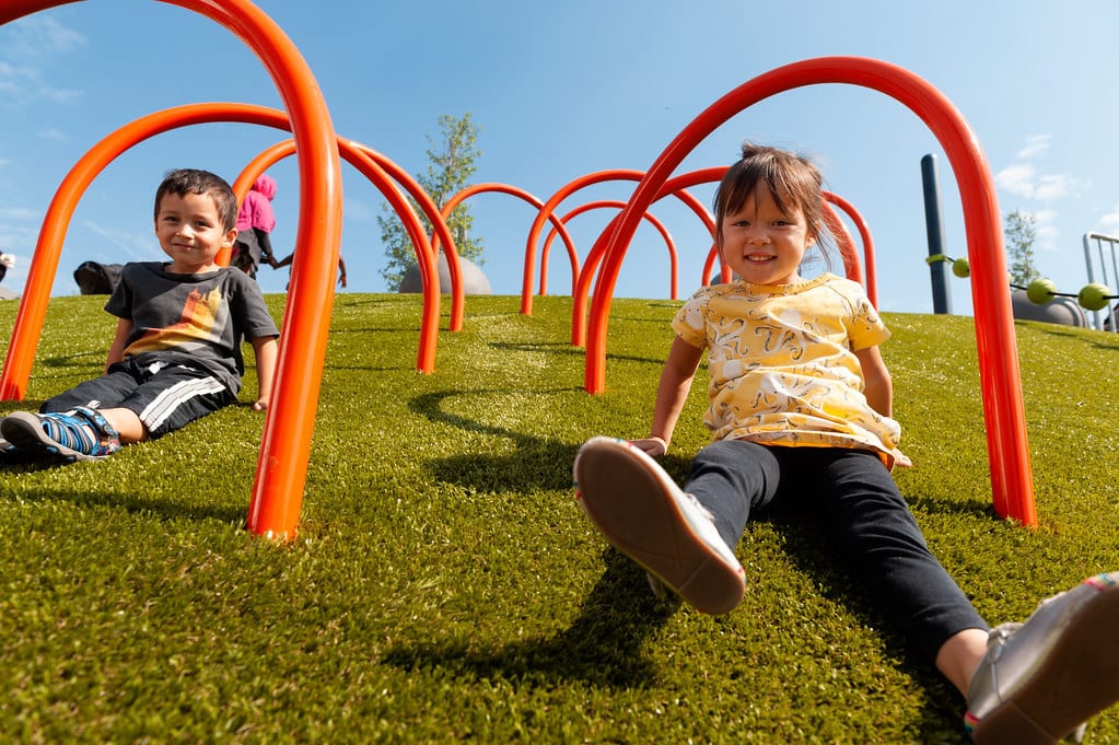 Children sliding down Playground Grass by ForeverLawn