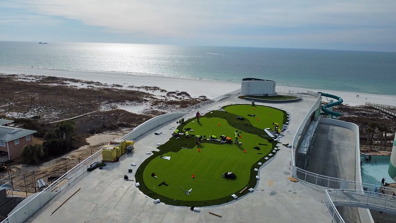 Group of men installing a turf golf green on a roof